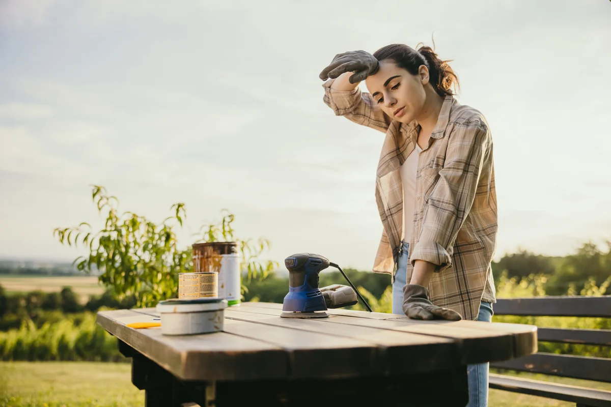 Woman outside sanding and staining outdoor furniture