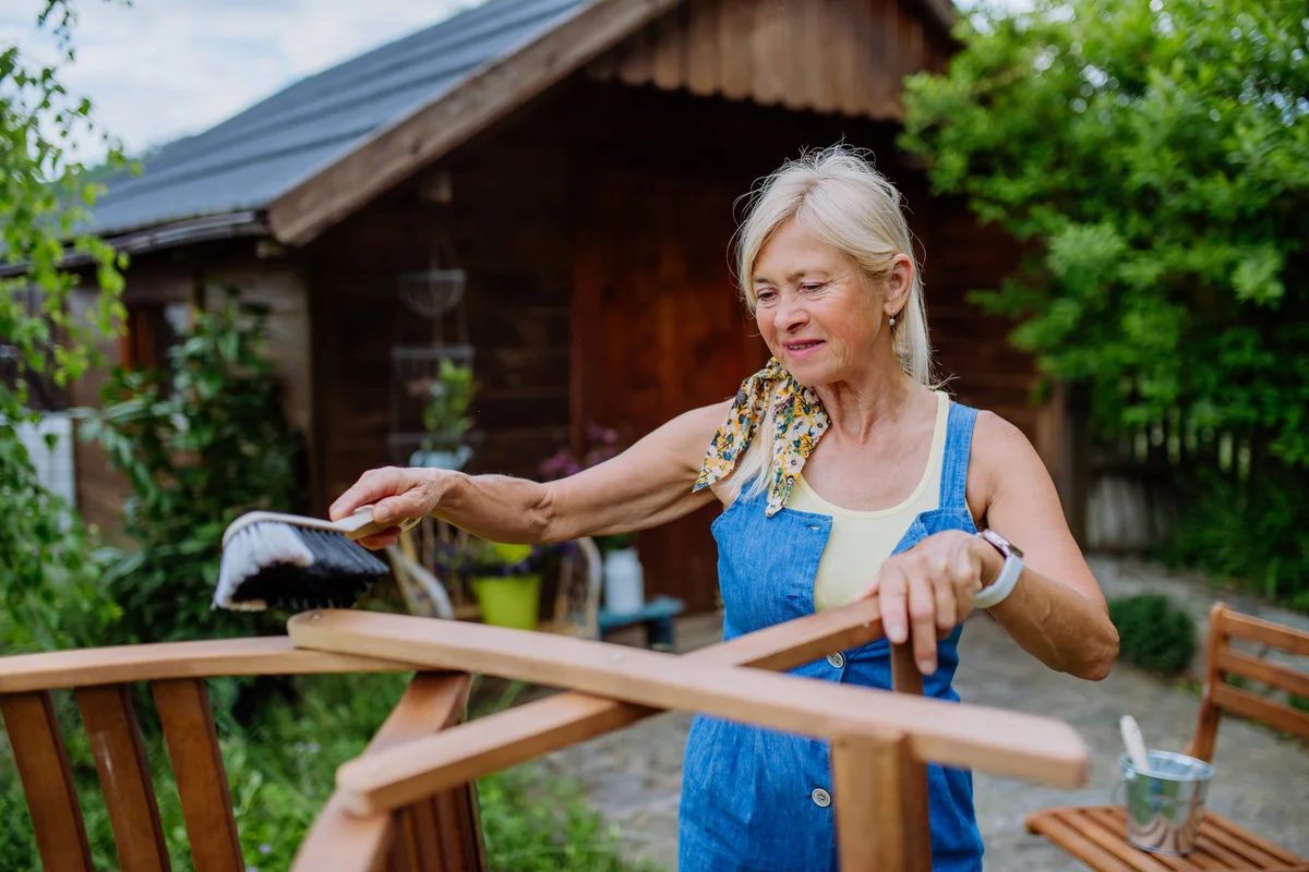 Senior woman scrubbing outdoor teak furniture