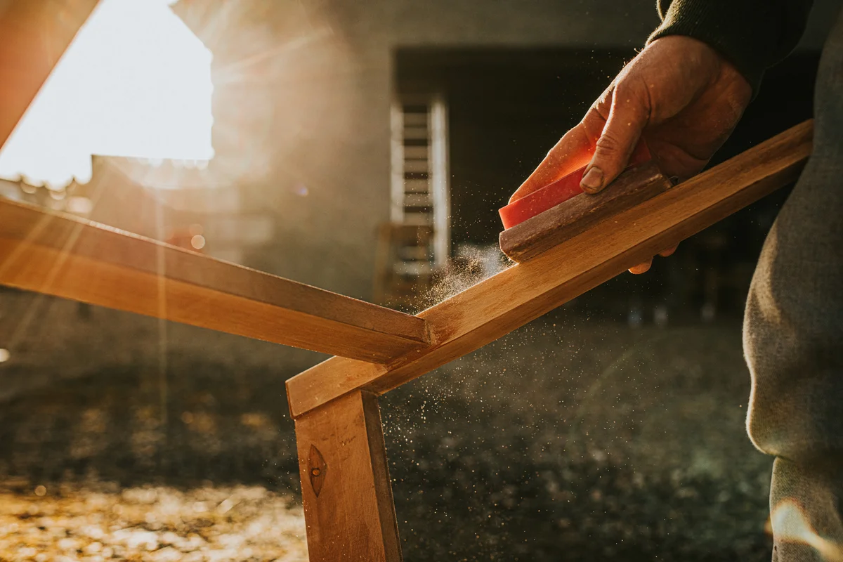 Man sanding and restoring teak furniture