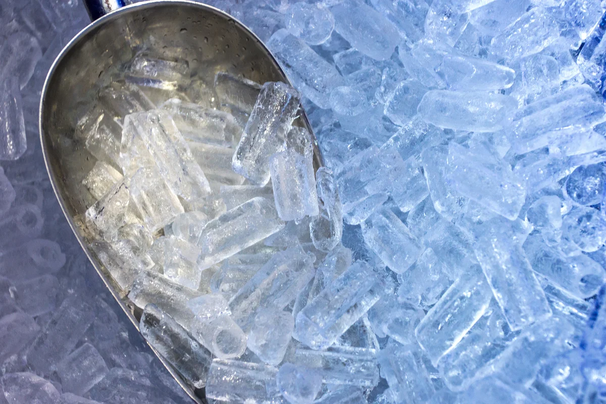 Scoop sitting in pile of ice from ice machine