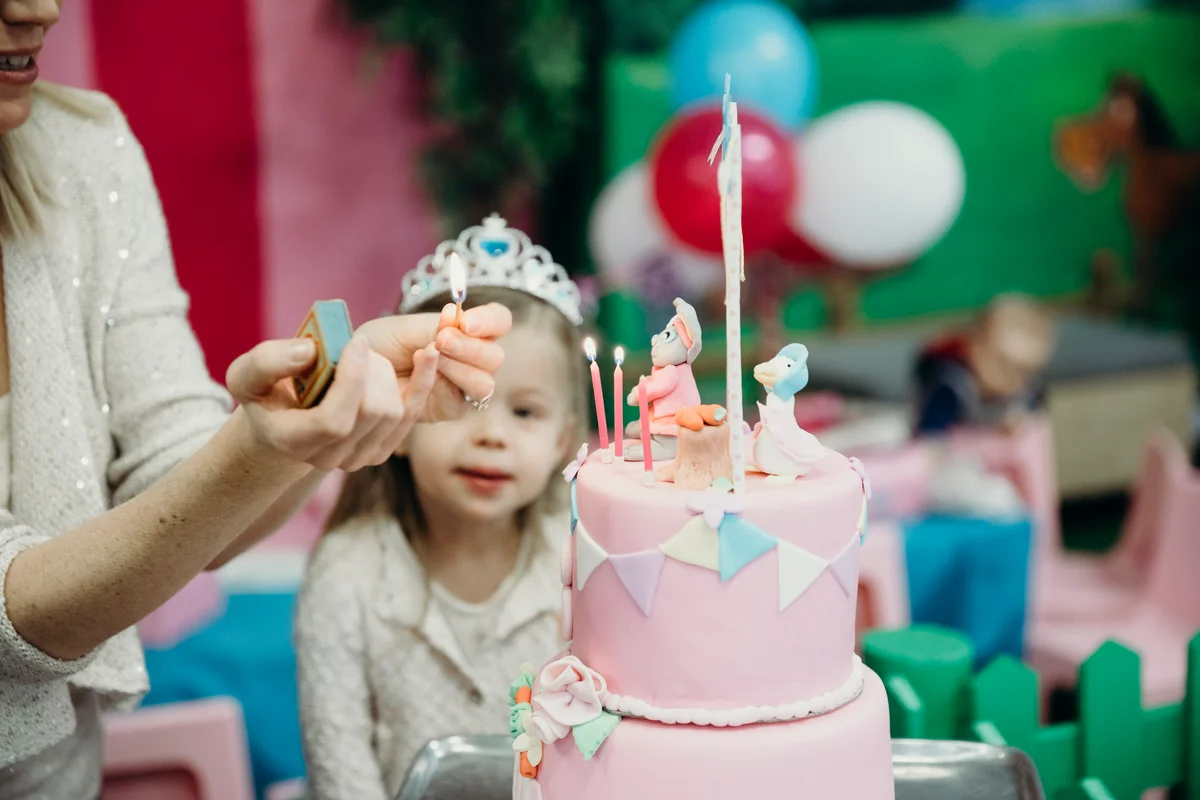 Young birthday girl watching her candles being lit at princess party