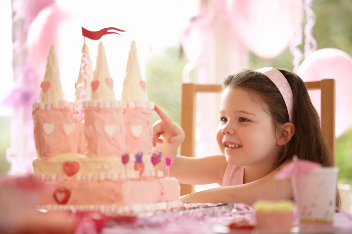 Five year old girl smiling at her princess castle birthday cake