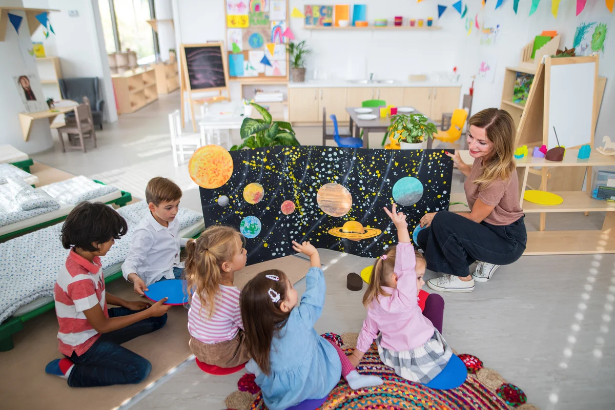 Teacher showing poster with planets to children