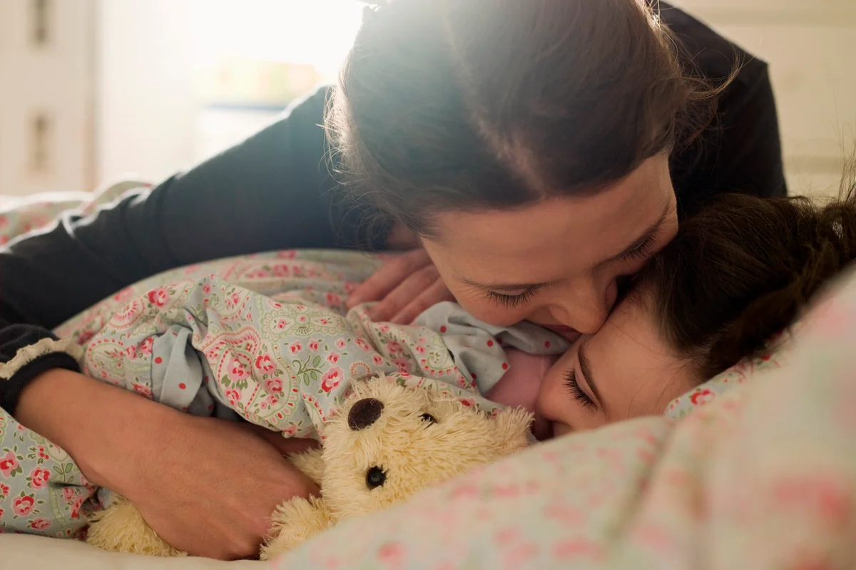Affectionate mother with daughter in bed