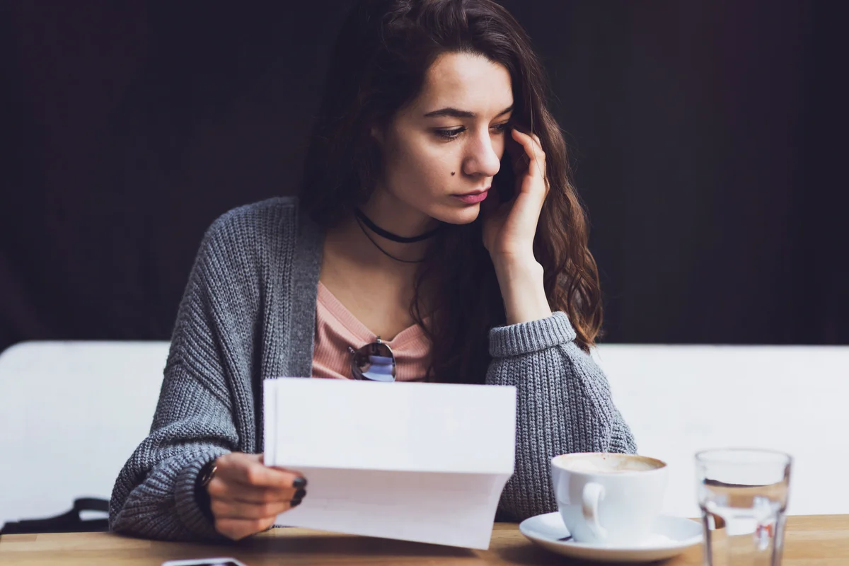 Sad woman holding letter in hand and thinking