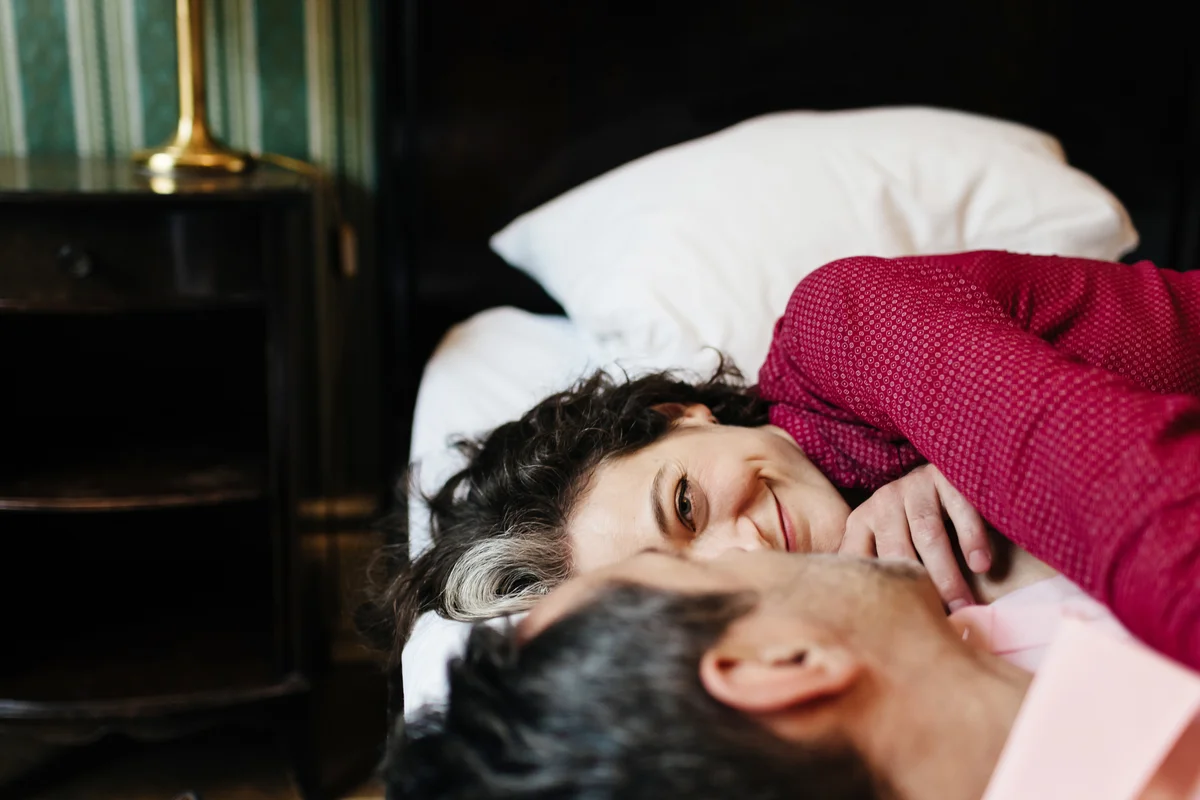 Mature couple laying in bed smiling at each other