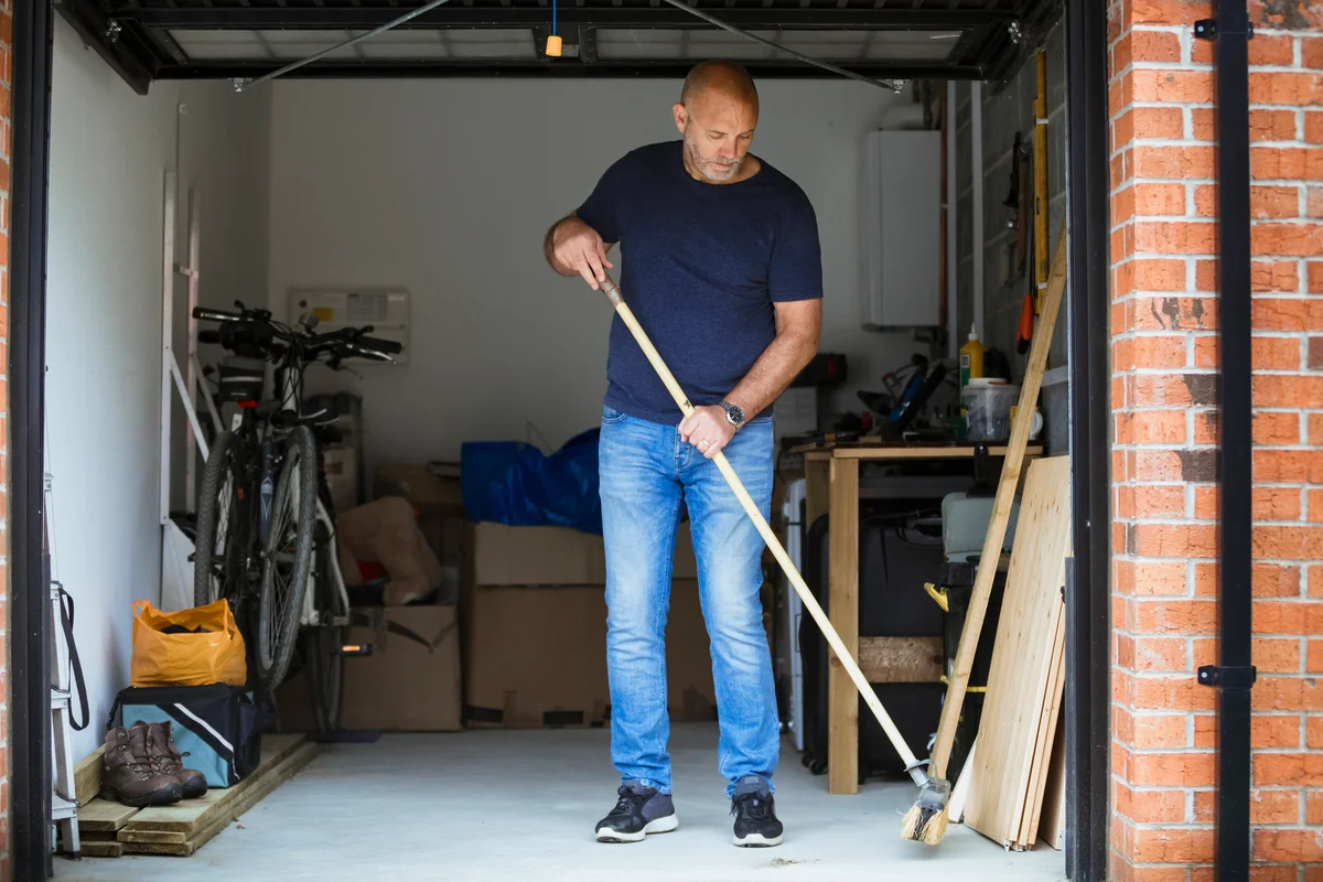 man sweeping garage floor
