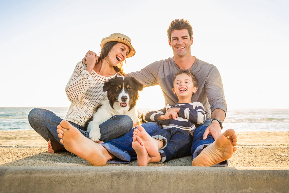 Caucasian family sitting with dog on beach