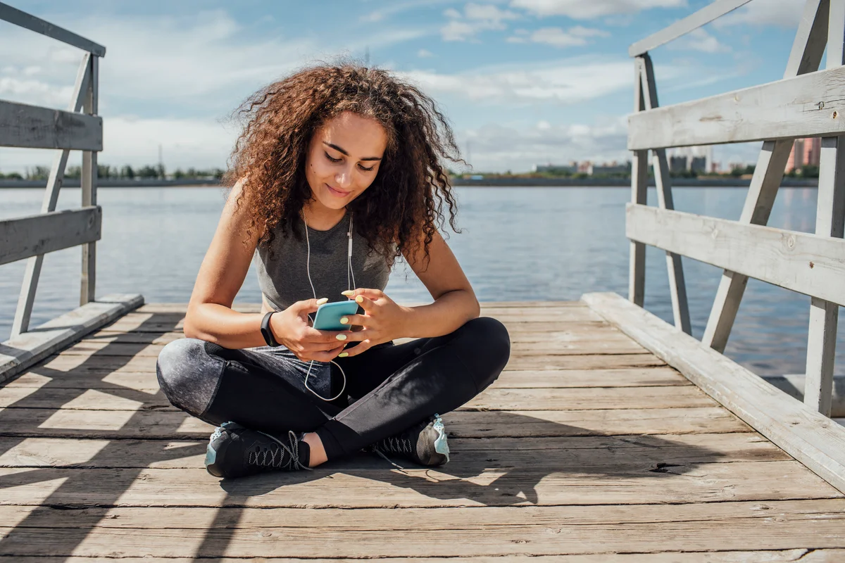 Girl sitting on dock and smiling at her phone