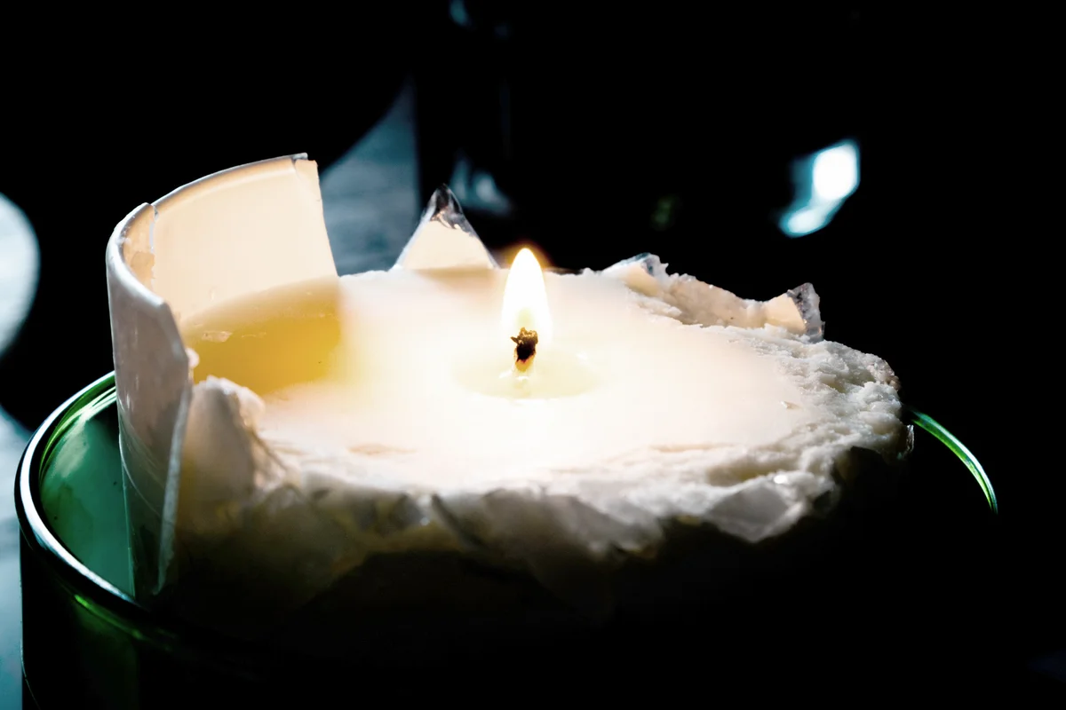 Broken lit candle in the darkness