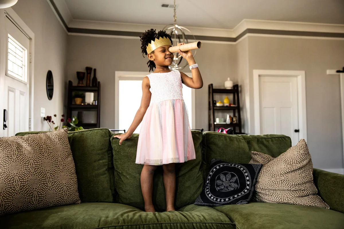 Young girl wearing homemade crown and looking through homemade telescope
