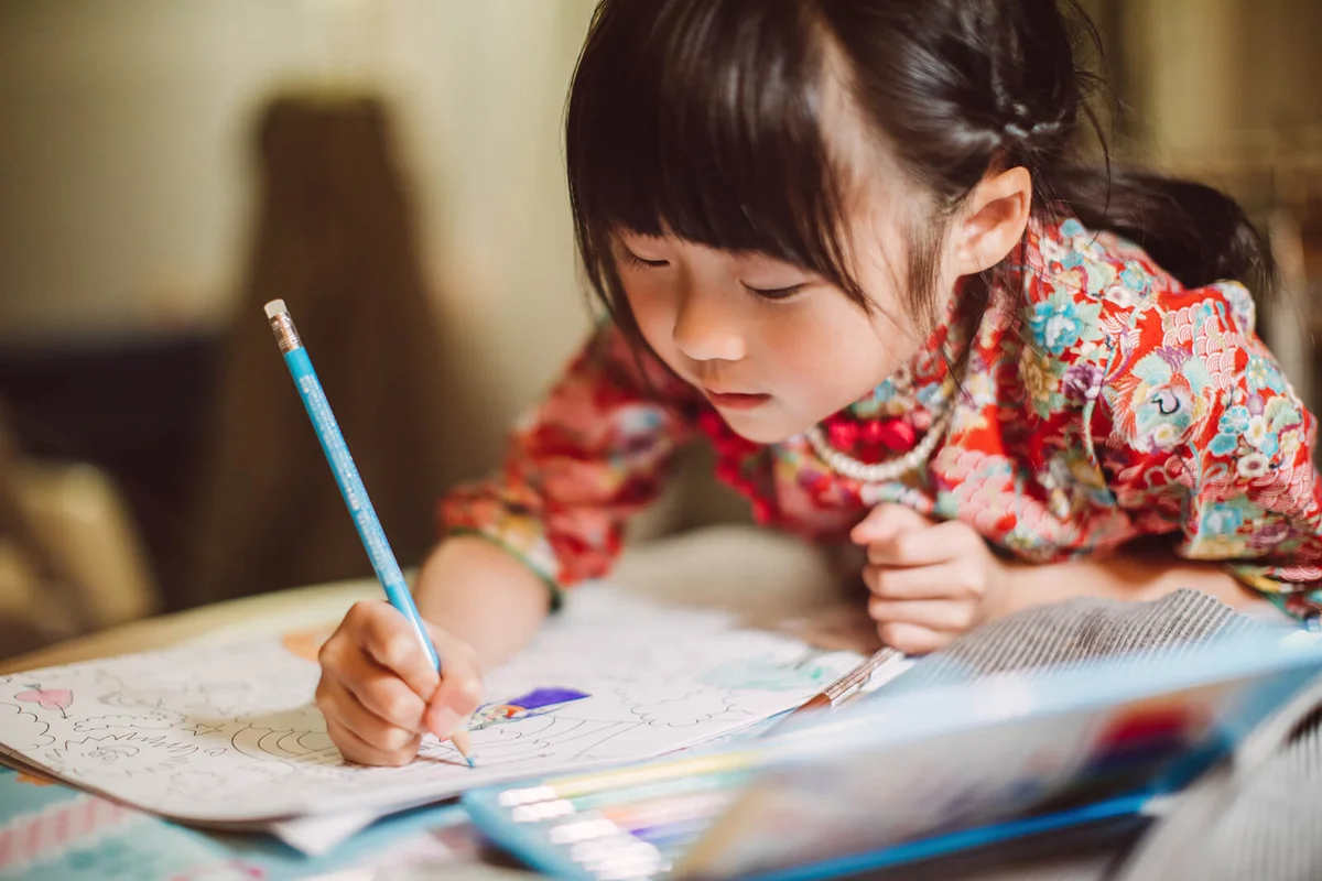 Girl colouring in a colouring book happily