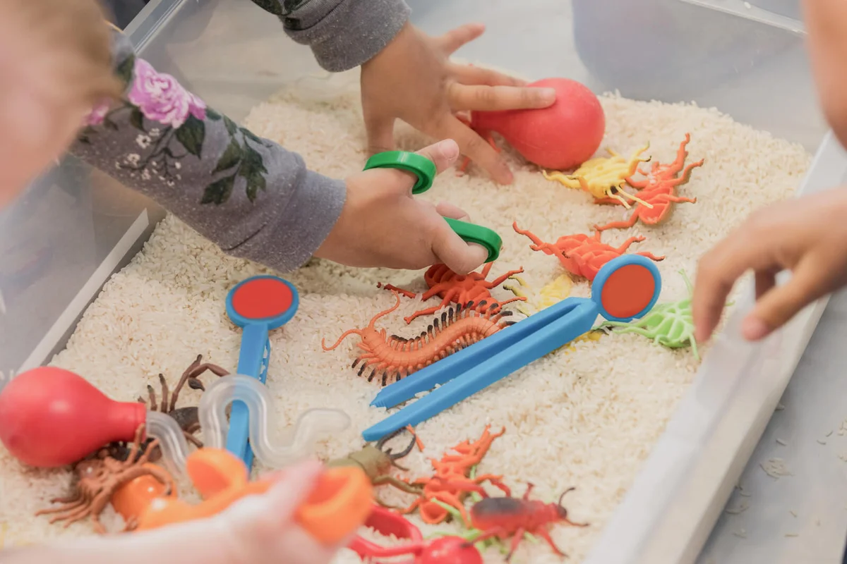 Unrecognizable children play in sensory bin