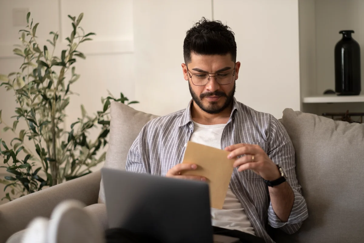 Adult male reading sitting on couch reading a letter