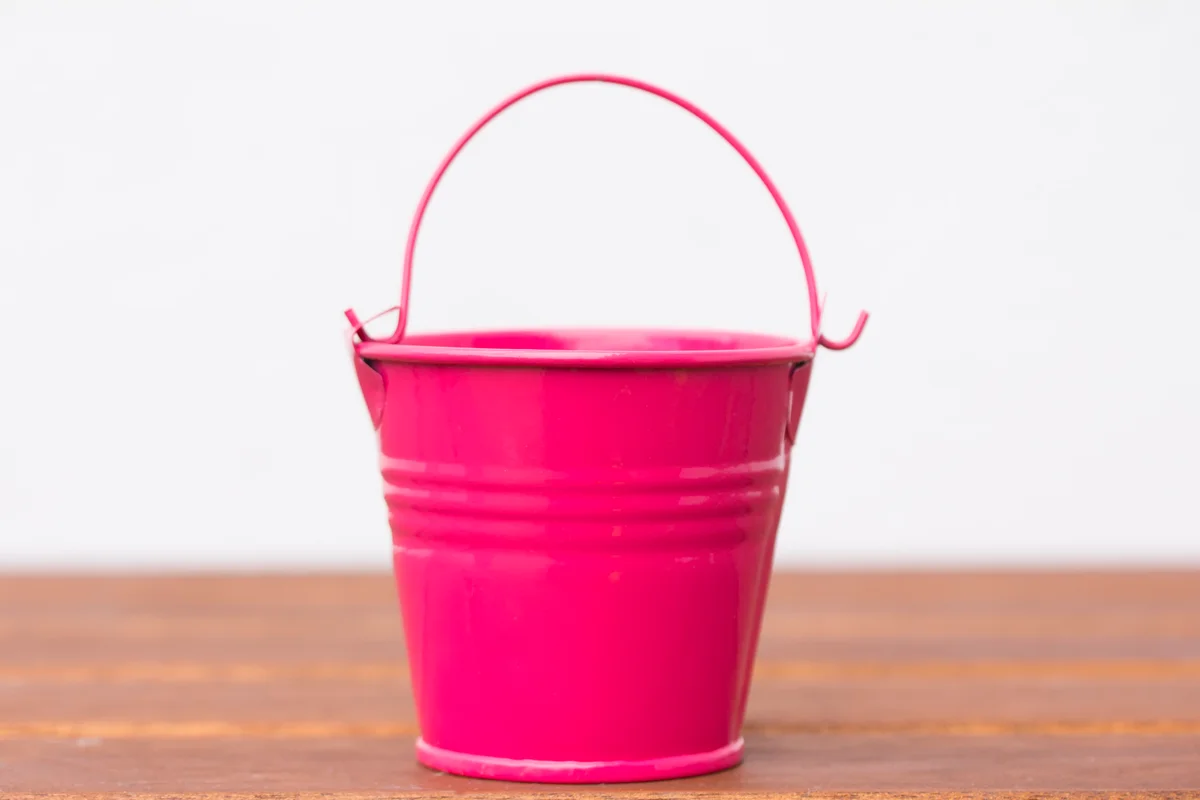 Pink metal pail sitting on wooden surface