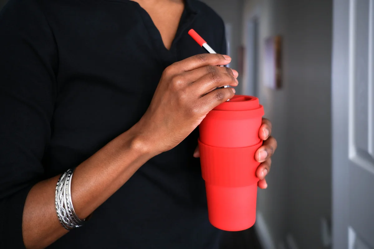 Woman holding red cup with reusable straw