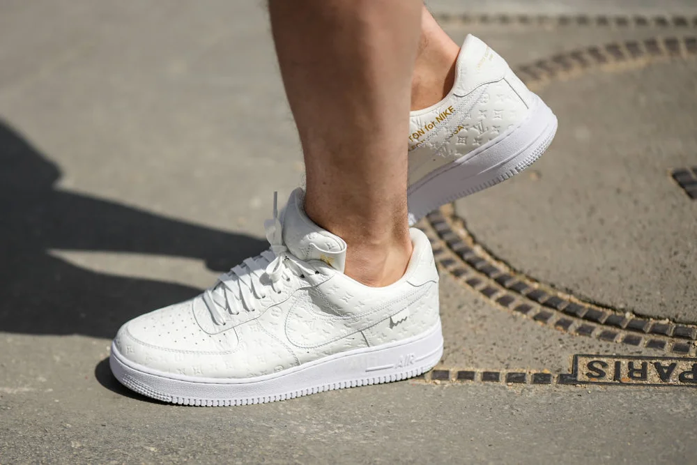 PARIS, FRANCE - JUNE 23: A guest wears white embossed LV monogram print pattern Air Force One sneakers from Nike x Louis Vuitton, outside the Louis Vuitton show, during Paris Fashion Week - Menswear Spring/Summer 2023, on June 23, 2022 in Paris, France. (Photo by Edward Berthelot/Getty Images)