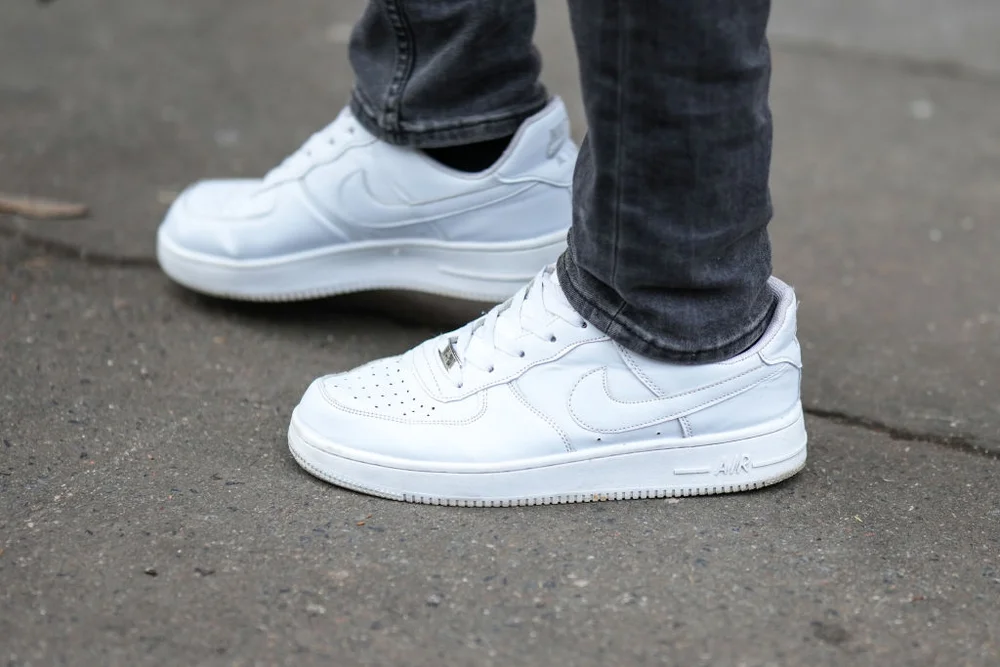 PARIS, FRANCE - JANUARY 19: A guest wears gray denim skinny pants, white shiny leather Air Force One sneakers , outside Rains, during Paris Fashion Week - Menswear Fall-Winter 2023-2024, on January 19, 2023 in Paris, France. (Photo by Edward Berthelot/Getty Images)