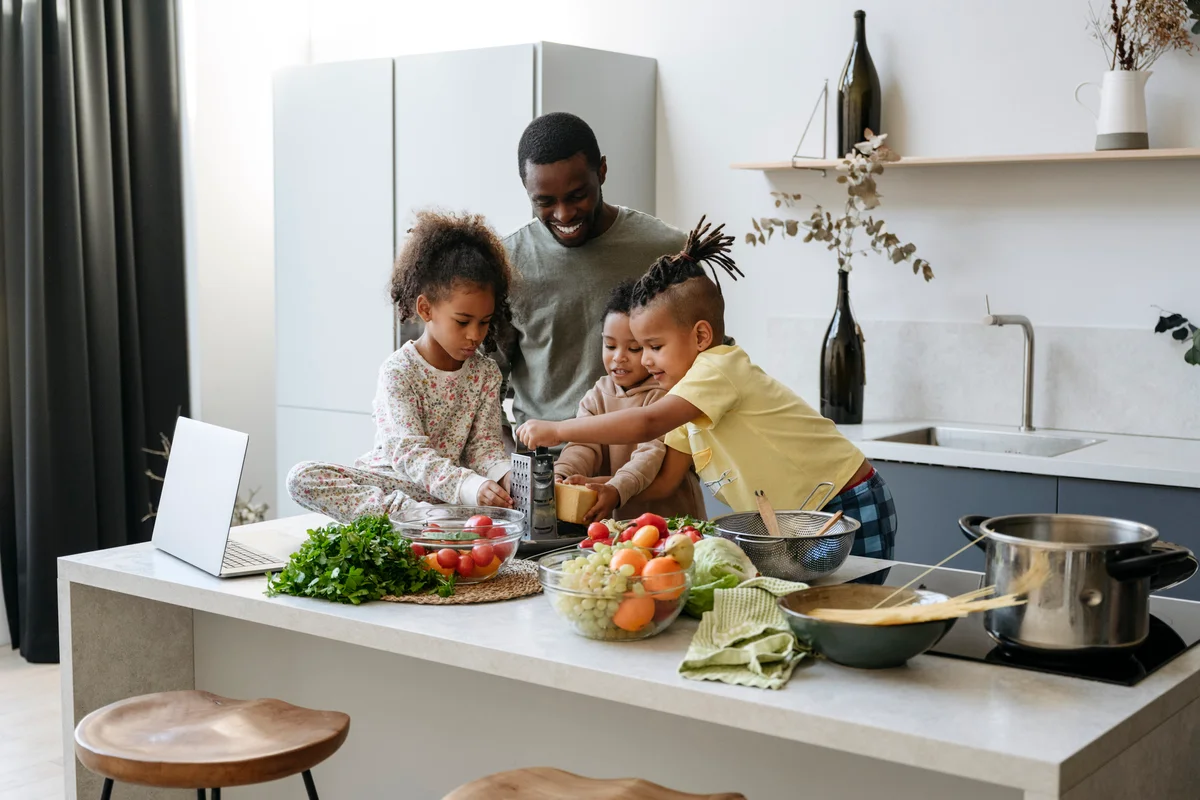 Father and young children prepping food on kitchen island