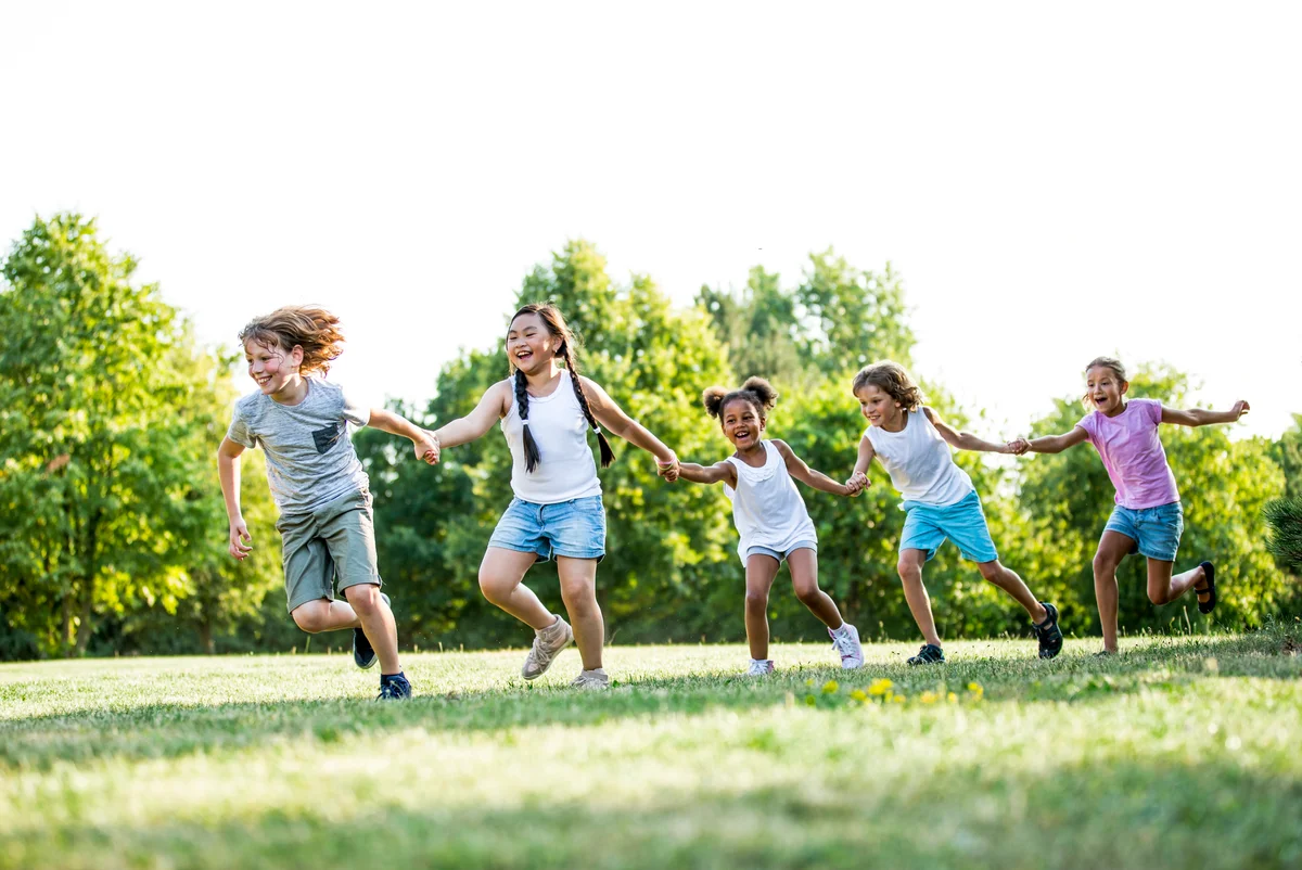 Children holding hands and running in a park