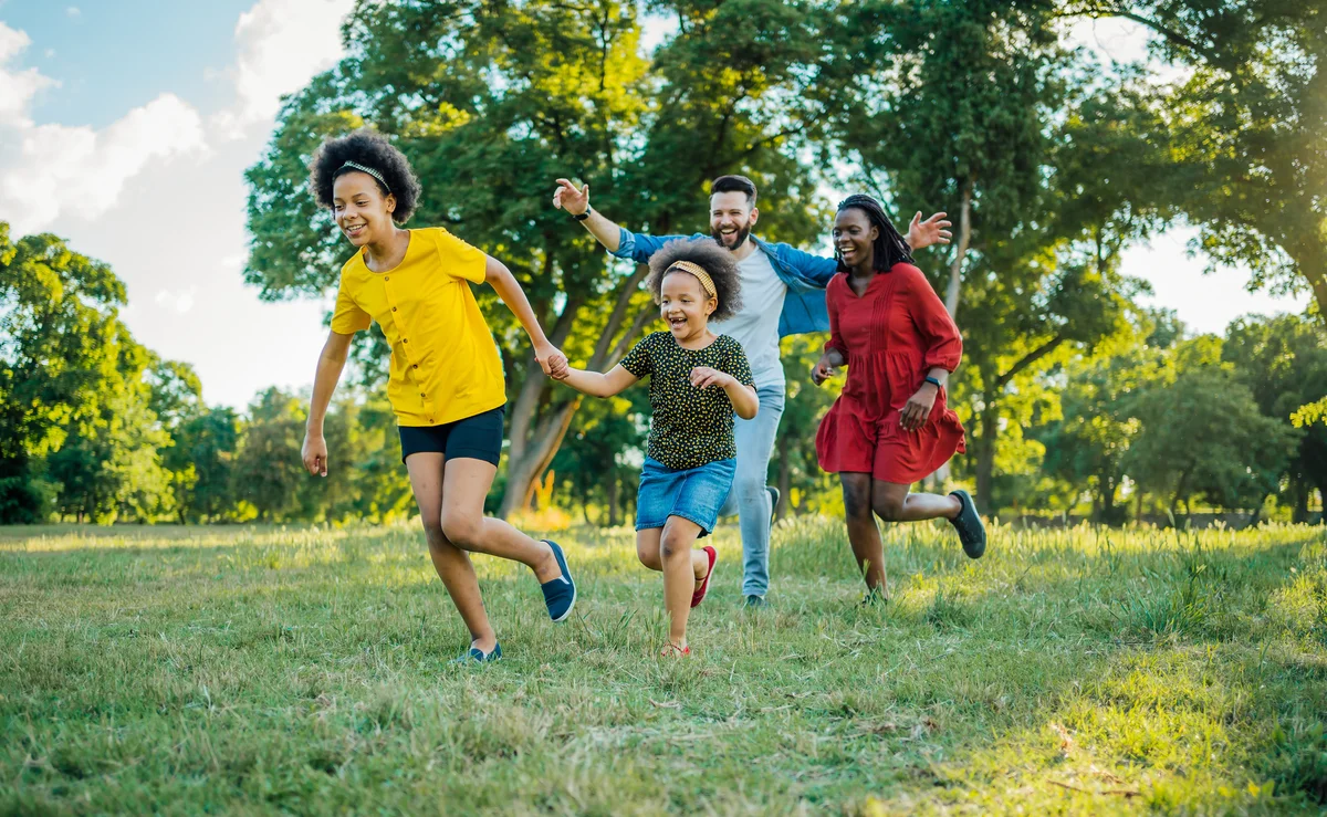 Family playing tag, dad chasing them with arms spread out like vampire