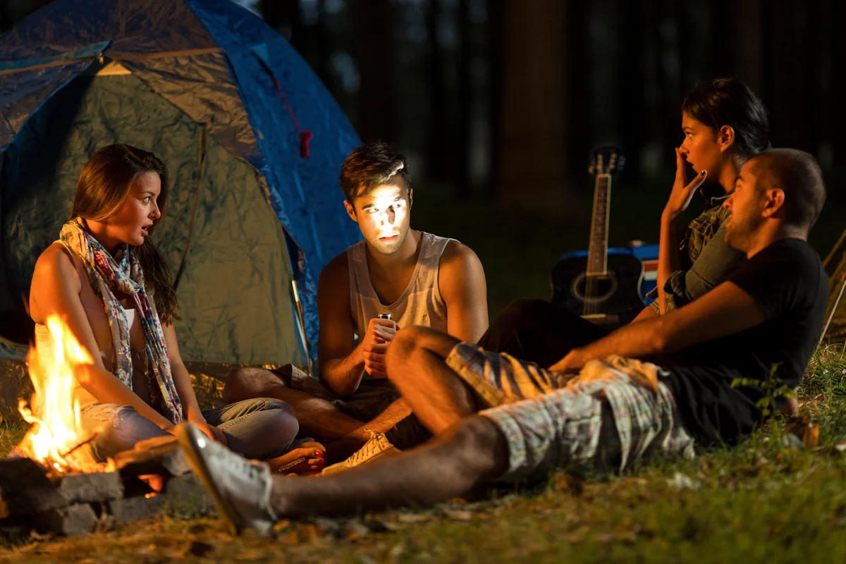Friends telling scary stories around a campire at night