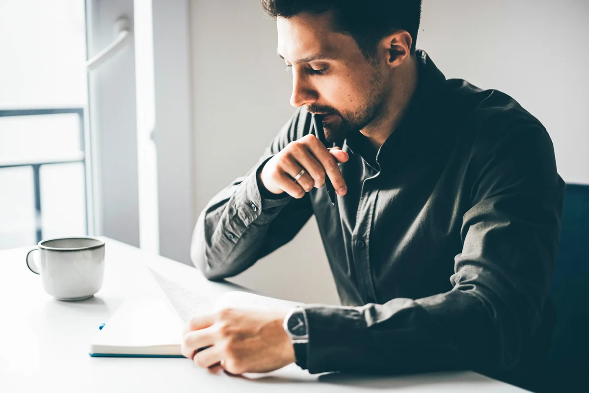 Businessman writing in notebook at home