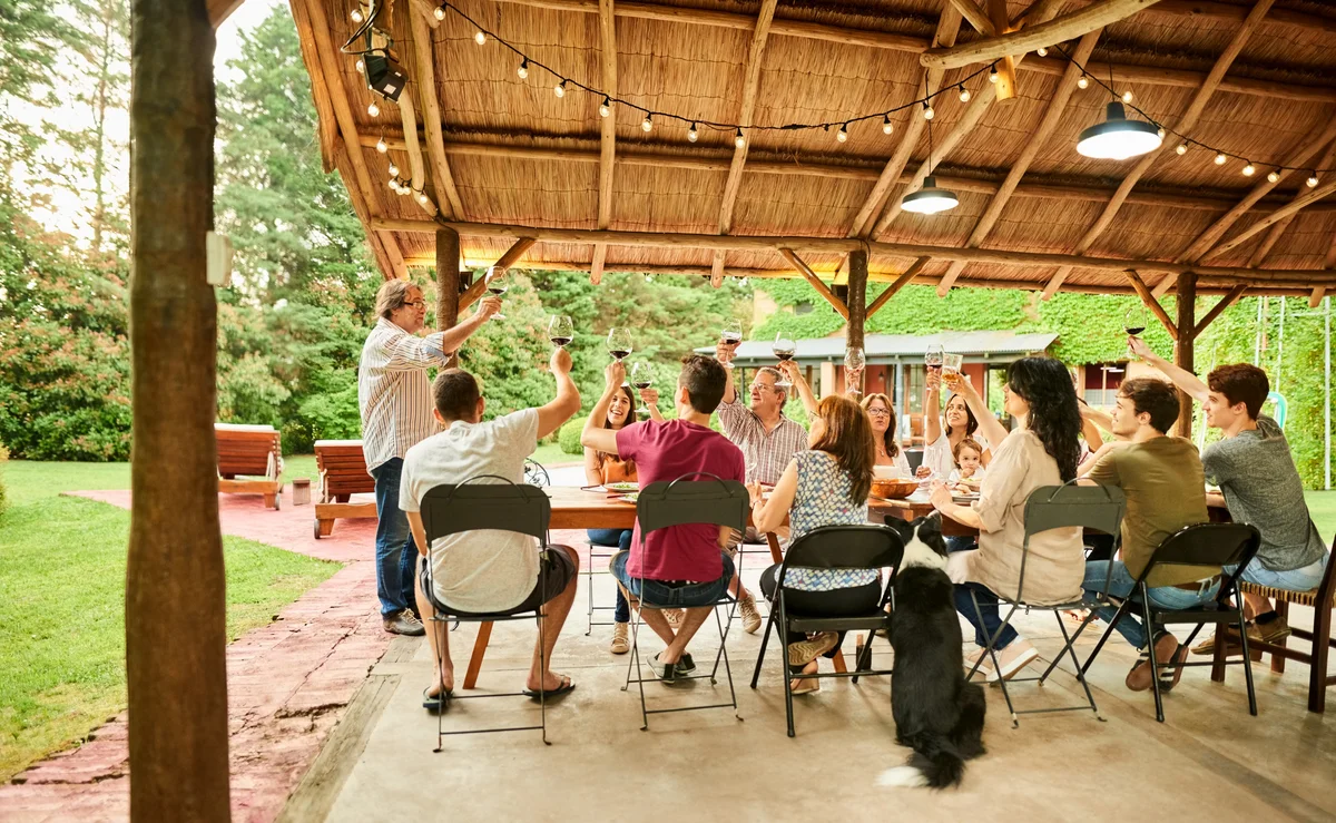 Person giving a speech to guests and family at outdoor dinner table