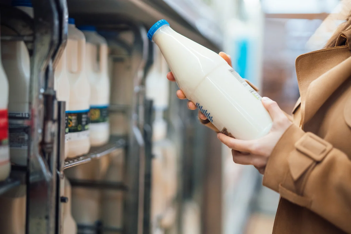 Woman holding a bottle of organic fresh milk in supermarket