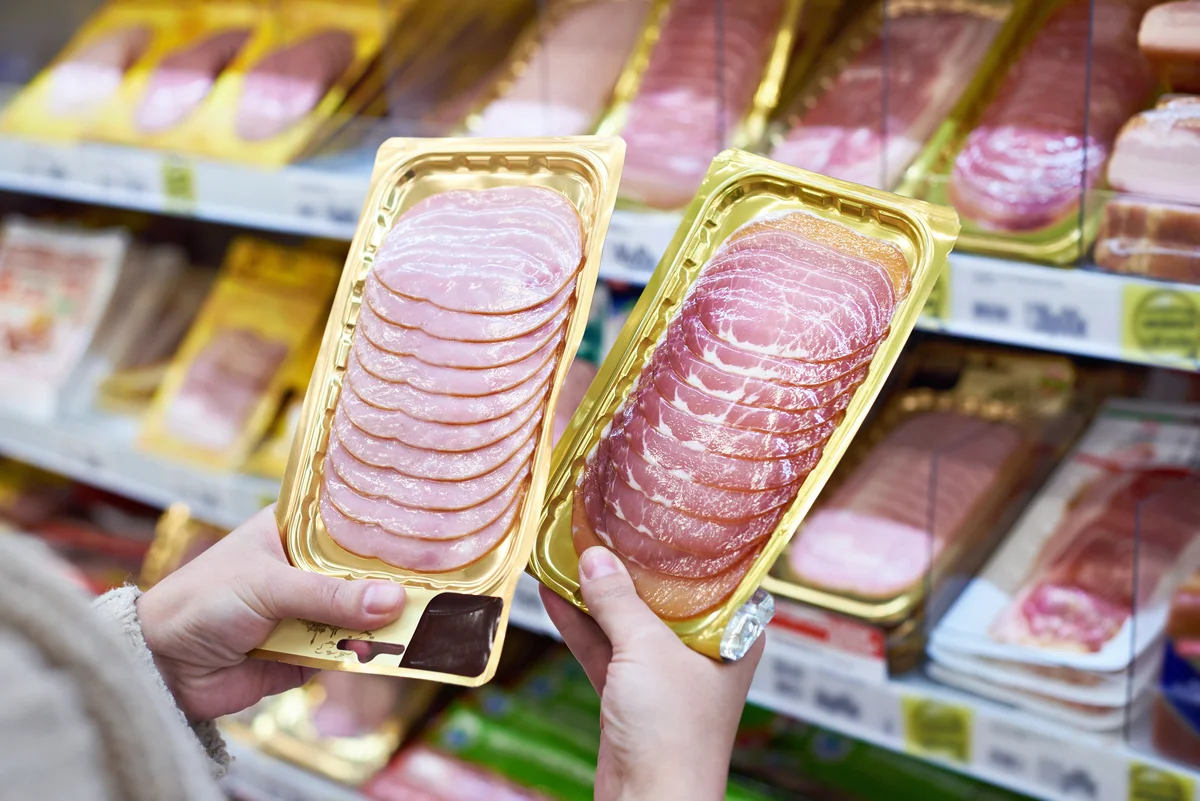 Woman chooses slice of ham at store