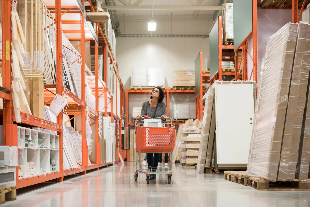 Woman looking up while pushing shopping cart in hardware store