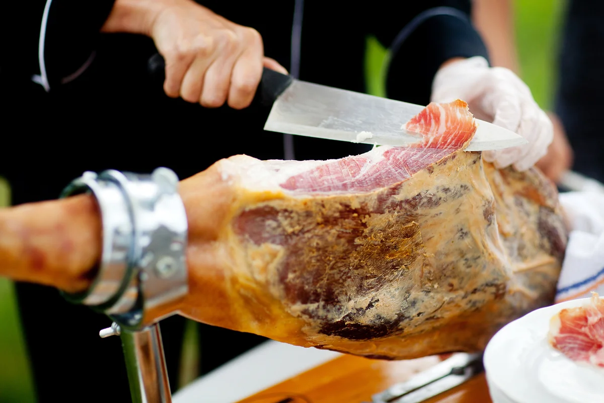Catering chef slices Prosciutto ham at a reception