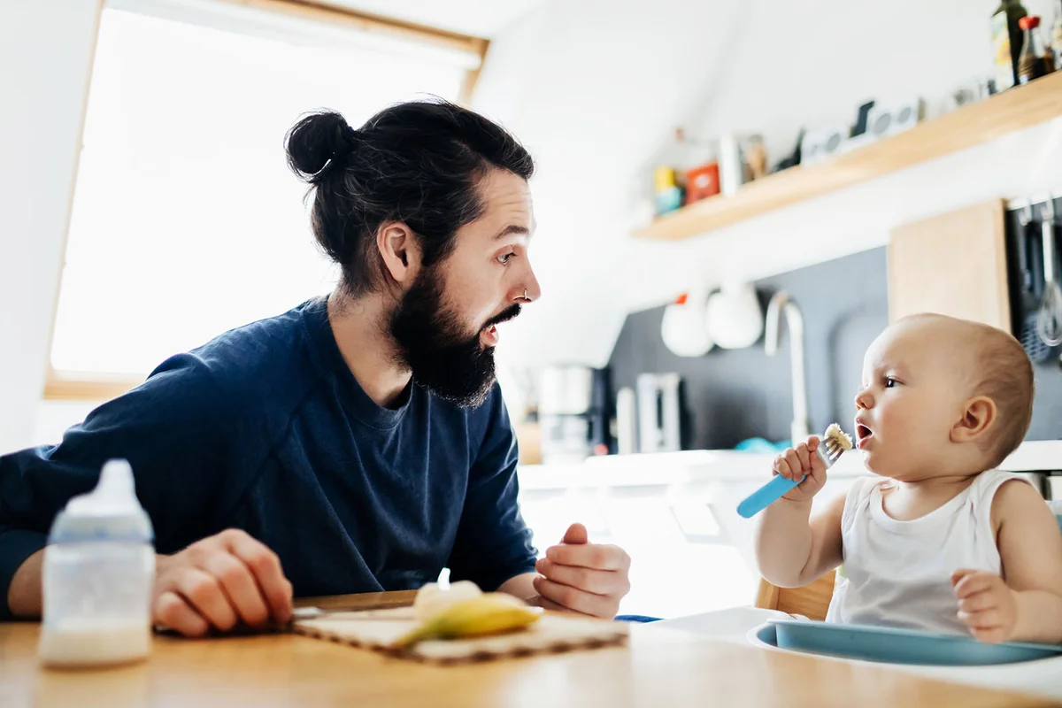 Father Helping Baby Eat Lunch