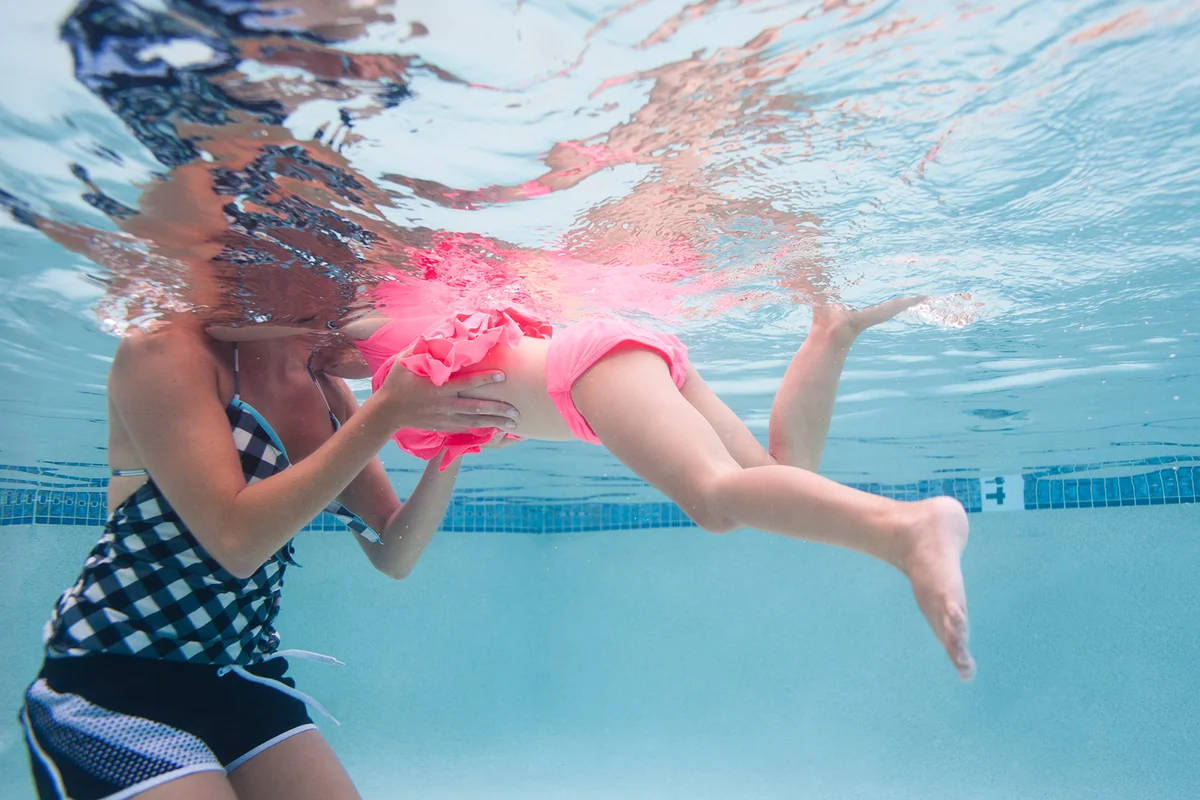 Mother with daughter swimming in pool
