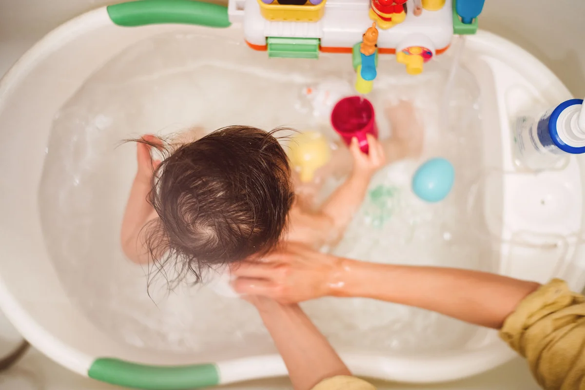 Mom taking bath for little baby in bathtub