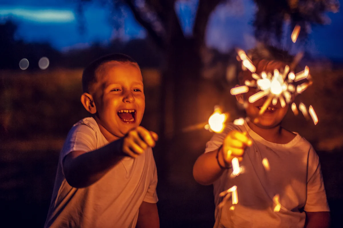 Boys have fun in the park with firework sparkles