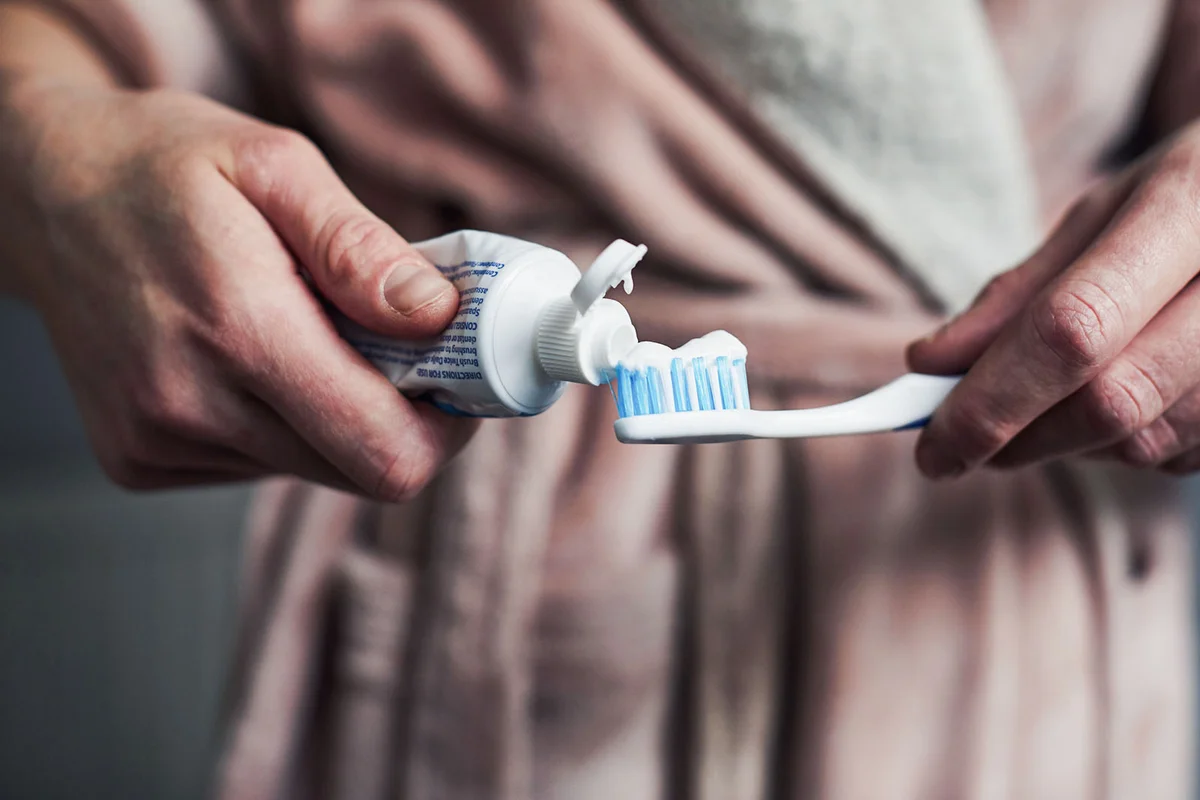 Woman putting toothpaste on a toothbrush