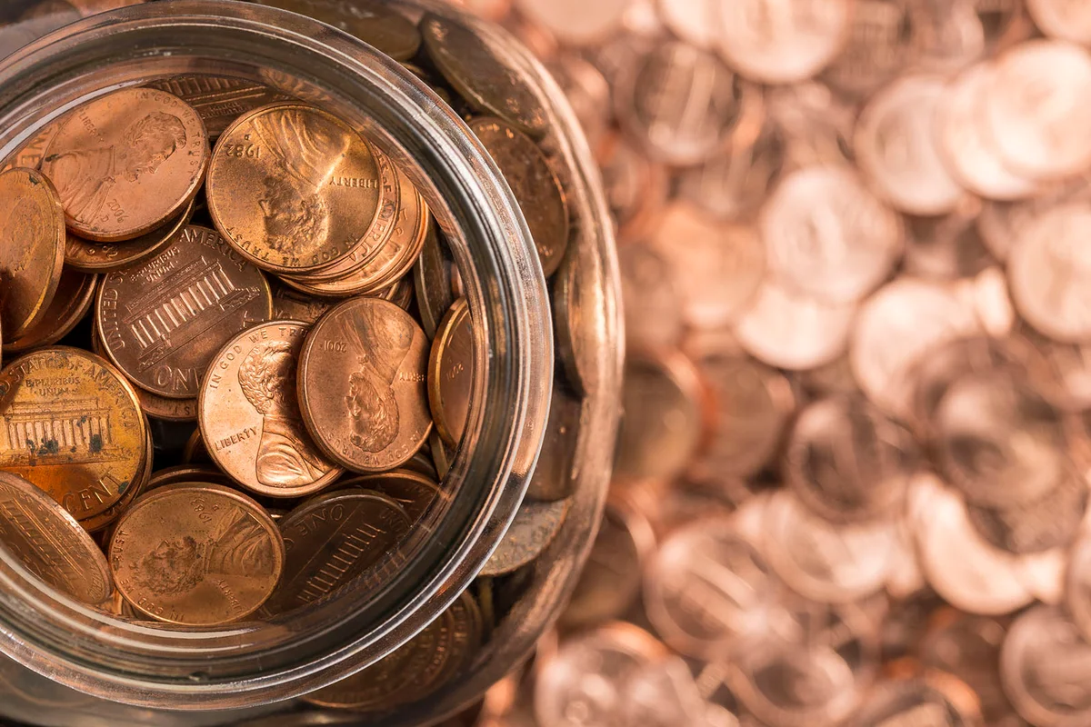 A jar of pennies surrounded by pennies