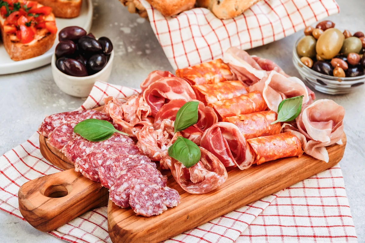 Food antipasto prosciutto ham, salami, olives and bread and Tomato and basil bruschetta Charcuterie board