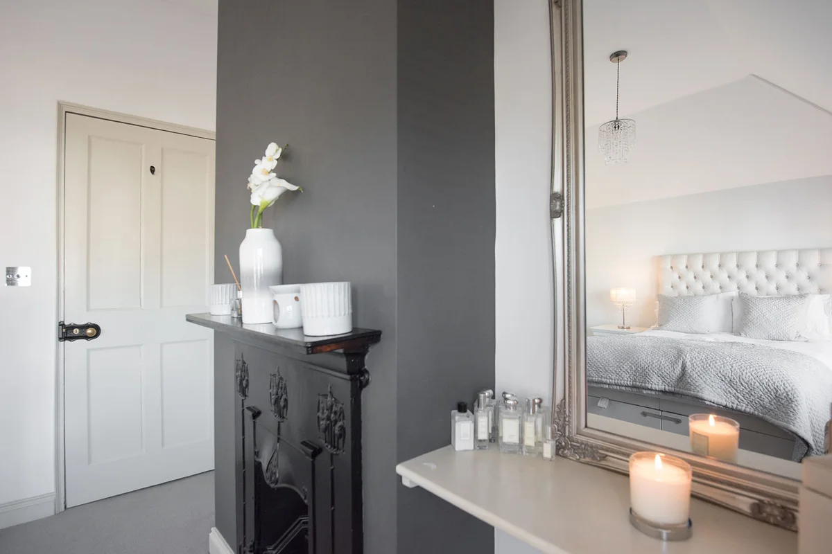 A general view of a master bedroom looking towards a original old black cast iron fireplace