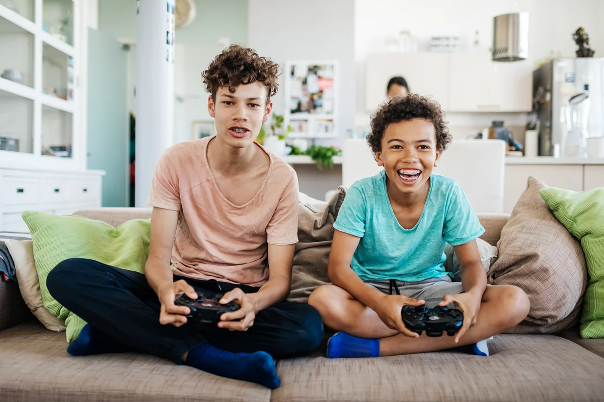 Two Brothers Sitting On Couch Playing Computer Games