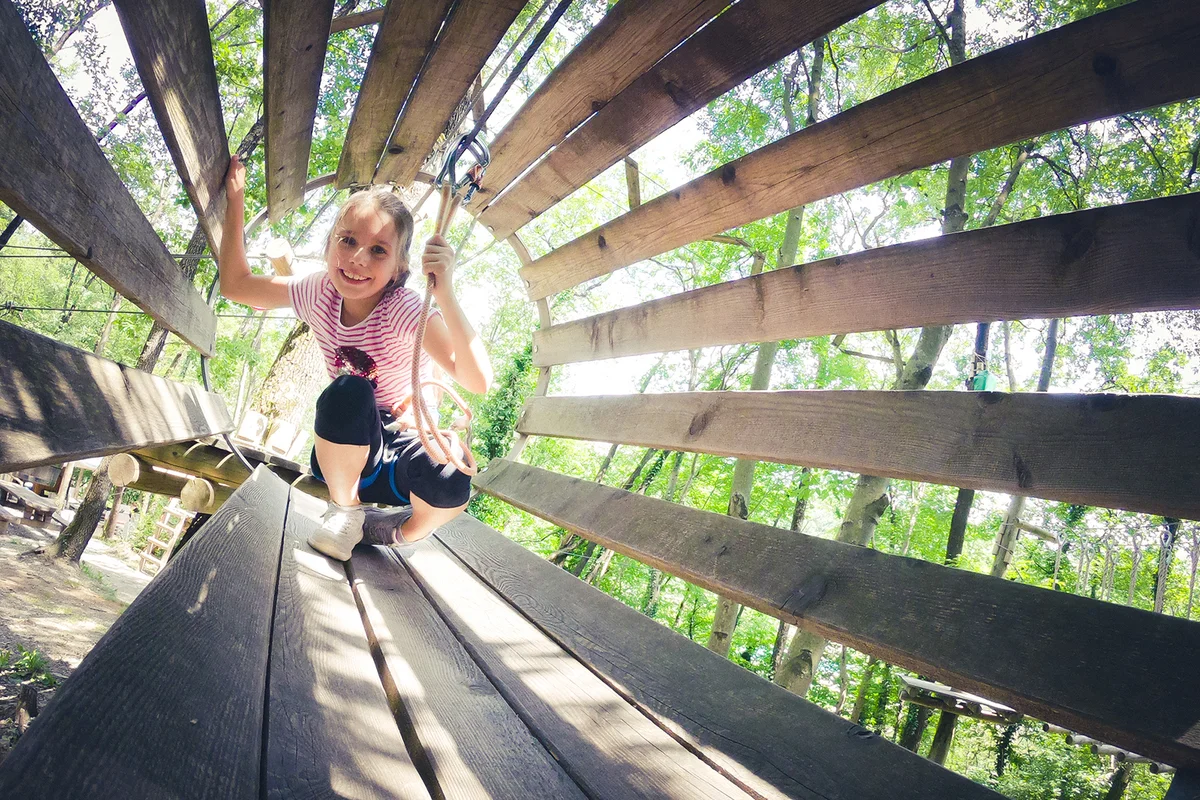 Smiling Young Girl Walking Thru Hanging Tunnel in Fun Park