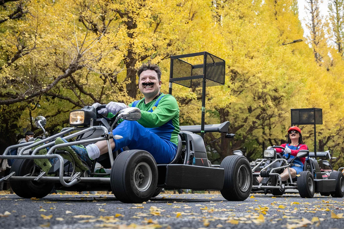 People drive go-karts while dressed in Super Mario costumes