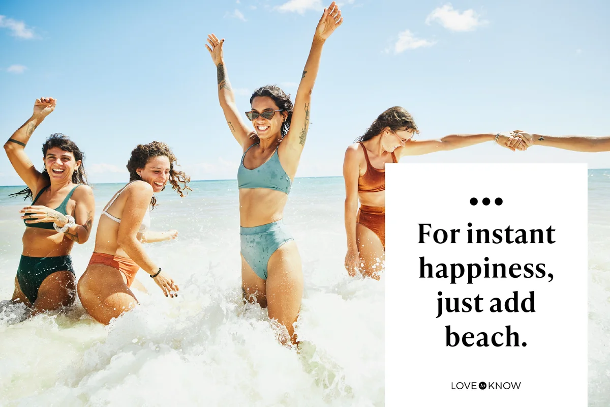 Wide shot of laughing and smiling female friends playing in surf at tropical beach