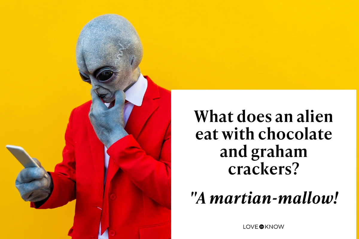 Portrait of man wearing alien costume and bright red suit using smart phone