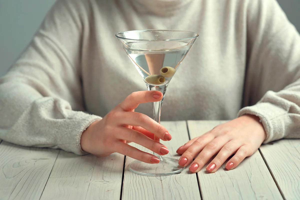 Woman's hands holding glass of Martini with olives