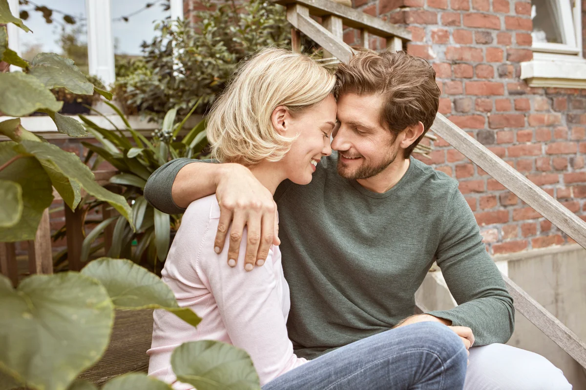 Happy couple sitting on stairs cuddling