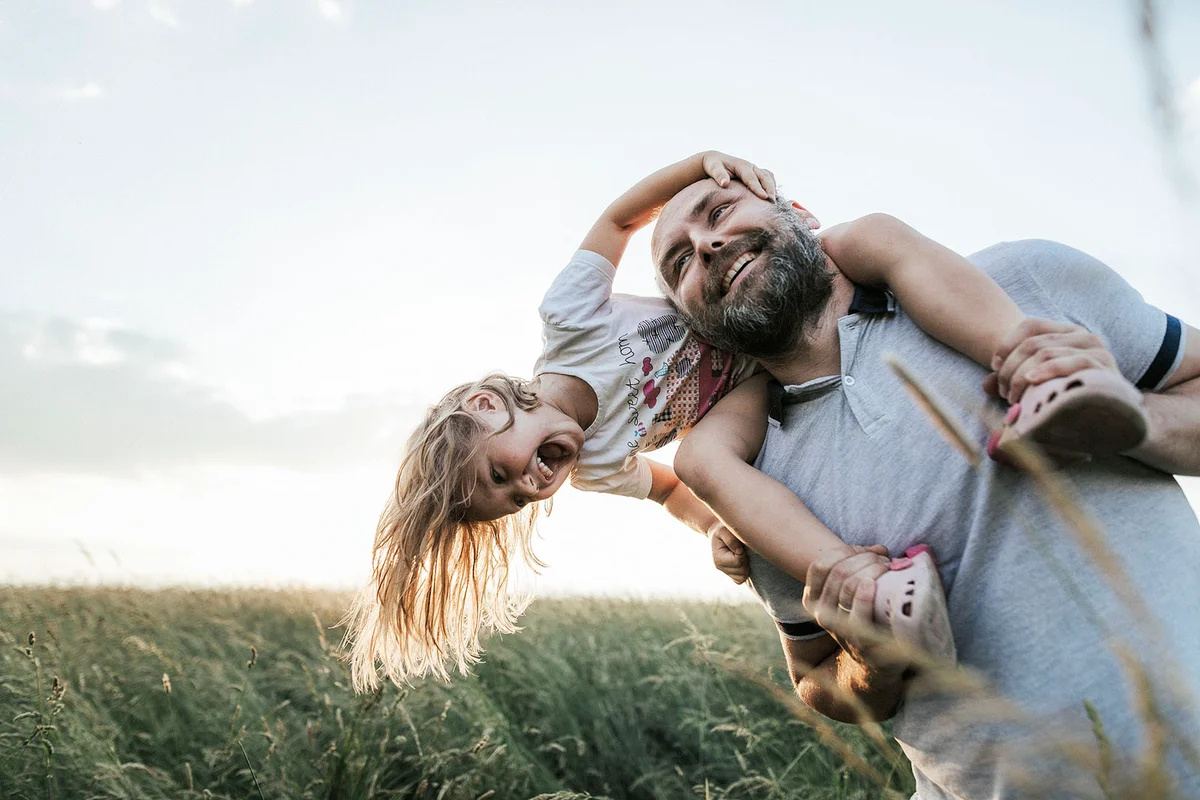Mature man playing with his little daughter in nature