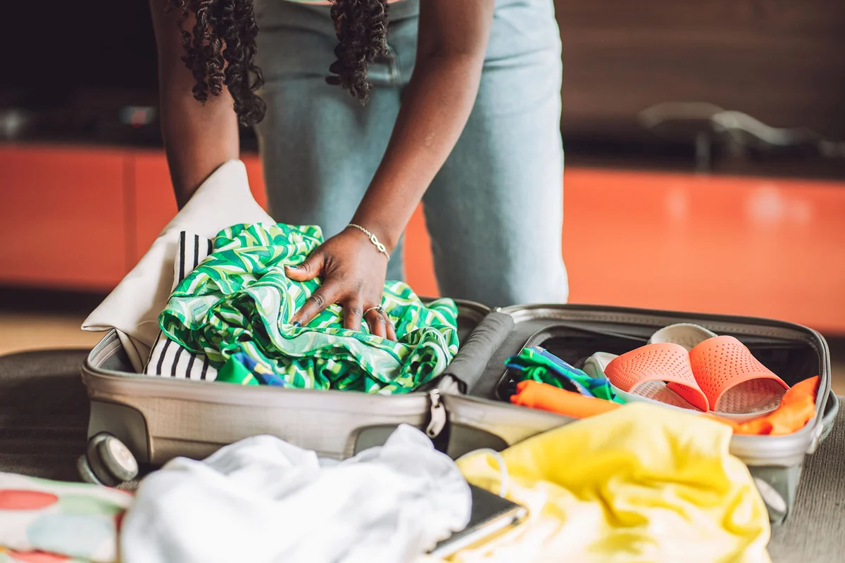 woman stacking clothes and shoes into bag case