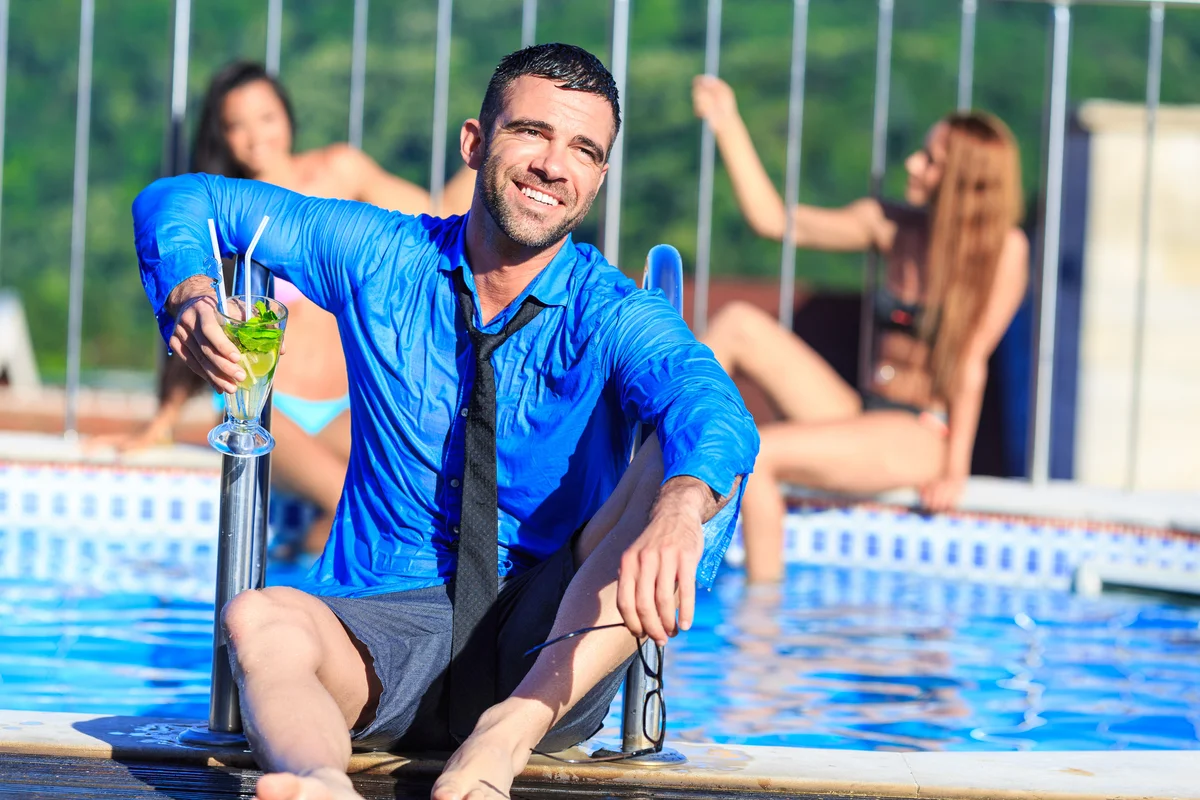 Young man drinking cocktail on poolside